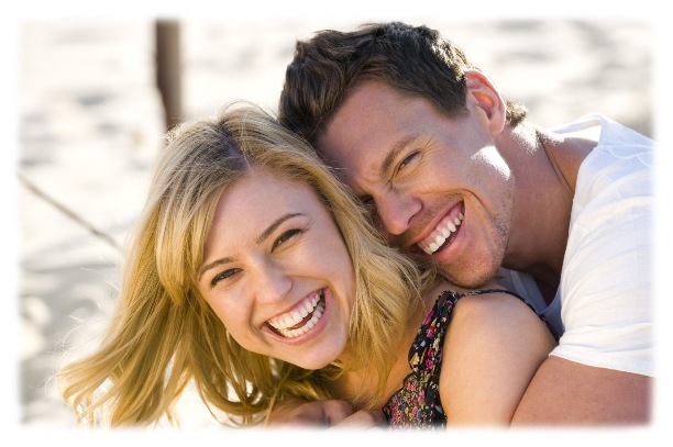 Happy couple embracing and laughing on the beach